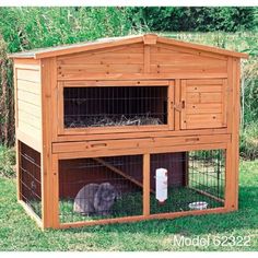 a large wooden rabbit house with two rabbits in it's cage and one bunny inside