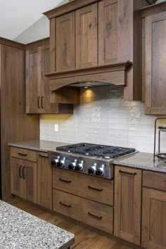 a stove top oven sitting inside of a kitchen next to wooden cupboards and counter tops