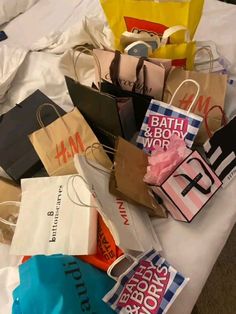 many shopping bags are piled on top of each other in the middle of a bed