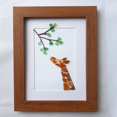 a paper giraffe hanging from a tree branch with green leaves on it's head