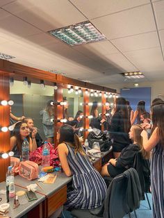 a group of women sitting around a table in front of a mirror with lights on it