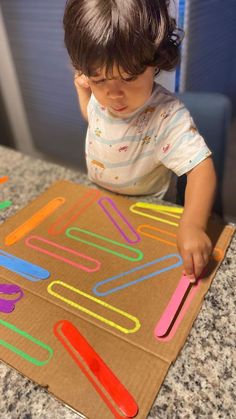 a young child playing with magnets on a cardboard box