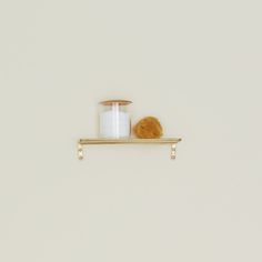 a candle and cookie on a shelf against a white wall with no one in it