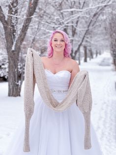 a woman with pink hair is wearing a white dress and holding a shawl in the snow