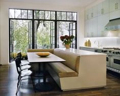 a kitchen with a table and chairs next to a window that looks out onto the woods