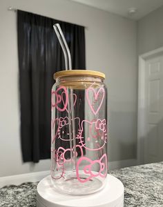 a glass jar with hello kitty designs on it and a straw sticking out of the lid