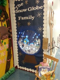 a child sitting in a rocking chair next to a snow globe display