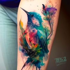 a watercolor tattoo with a bird on it's arm and colorful paint splatters