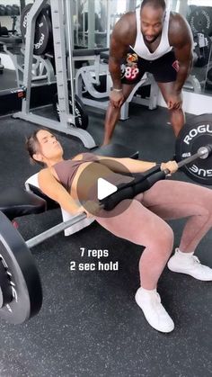 a woman doing squats with a barbell in front of her and another man behind her