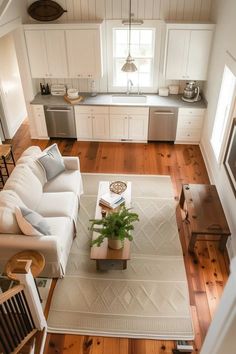 an overhead view of a living room and kitchen area with hardwood floors, white couches, coffee table