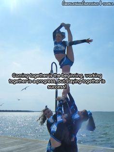 two women are doing acrobatic tricks on the dock by the water with their hands in the air