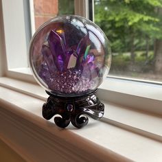 a purple crystal ball sitting on top of a window sill