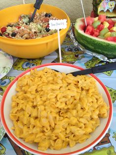 there is a plate of macaroni and cheese on the table with watermelon