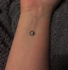 a woman's wrist with a small sun and moon tattoo on her left arm