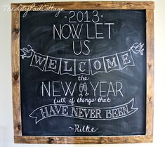 a chalkboard with some writing on it in front of a white wall and wooden frame