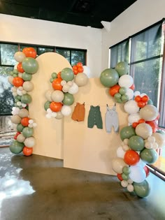 an arch made out of balloons with clothes hanging on the wall in front of it