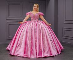 a woman in a pink ball gown standing with her hands on her hips and looking at the camera