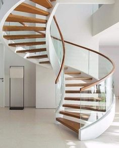 there is a spiral staircase in the middle of this room with glass railings and wood handrails