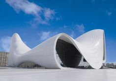 a large white building with a curved roof and sky in the backgroung