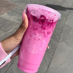 a hand holding a pink starbucks drink with blueberries and ice cream on it's side