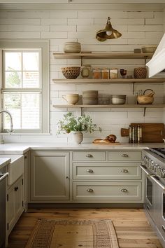 a kitchen with white cabinets and open shelving on the wall above the stove top