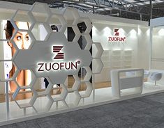 an exhibition stand with white furniture and signs on the walls that read zuofun