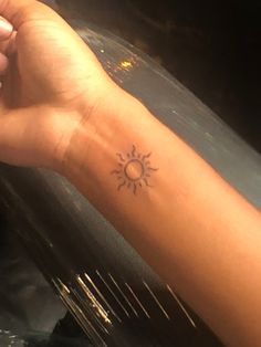 a woman's arm with a small sun tattoo on it