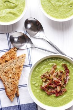 three bowls of soup and two spoons on a table