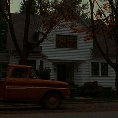 an old truck parked in front of a white house