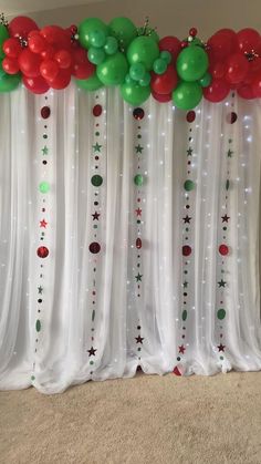 balloons and streamers are hanging from the curtain in front of a christmas themed backdrop