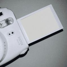 a white camera sitting on top of a table next to an empty card holder and pen