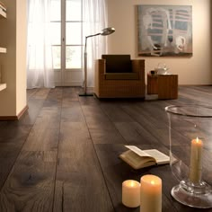 a living room filled with furniture and candles on top of a hard wood floor next to a window