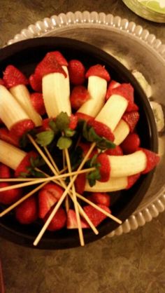 strawberries and apples arranged in a bowl on a table with toothpicks sticking out of them