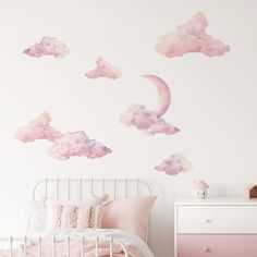 a pink and white bedroom with clouds painted on the wall, bedding and nightstand