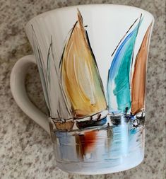 a coffee cup with sailboats painted on the outside and inside, sitting on a granite countertop