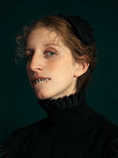 a woman with freckled hair wearing a black dress and headband, looking at the camera