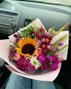 a person holding a bouquet of flowers in their hand while sitting in a car seat