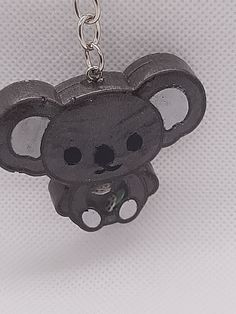 a keychain shaped like a koala bear on a white background with black dots