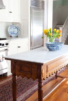 a bowl with yellow flowers on top of a table in a kitchen next to an oven