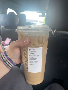 a person holding up a cup of coffee in the back seat of a car