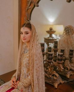 a woman in a bridal gown sitting on a table with a mirror behind her