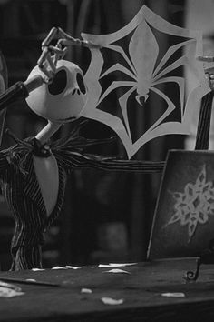 a black and white photo of two figurines on top of a table with paper cutouts