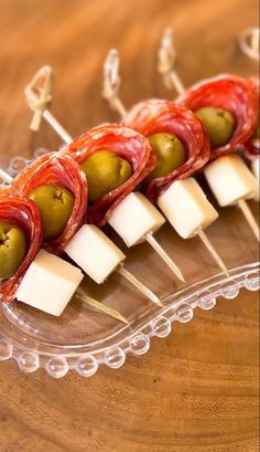 several skewered olives and cheese on a clear plate