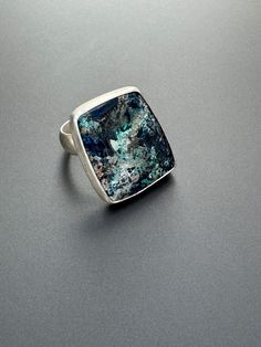 This is a gorgeous piece of chrysocolla set in sterling silver. The ring and band are made from sterling silver. The stone stone is large but not huge so it makes a really nice size ring. The colors in the stone are so vibrant, so beautiful it reminds me of earth. The ring is size 7 1/2.  The stone is about 1 inch x 3/4 inch and the band is about 1/4 in wide.  Chrysocolla :  Expression, awareness, and the drive for higher knowledge - there are many things the Teaching Stone has to show us. For those who are ready to up the ante when it comes to standing in their personal power, Chrysocolla can be an amazing tool for washing away those self-limiting beliefs and negative emotions that can hold you back. It's a stone of massive self-awareness and can be an exceptional tool for those who want Personal Power, Show Us, Rings Statement, Favorite Things Gift, Statement Rings, Silver Ring, Really Cool Stuff, 4 Inch, Jewelry Rings