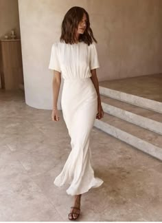 a woman in a white dress walking down some steps