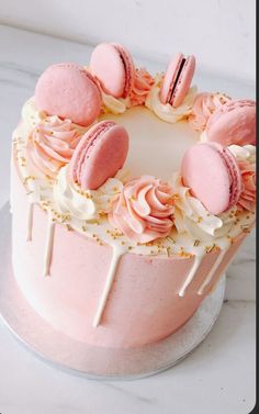 a pink cake with white icing and macaroons on top