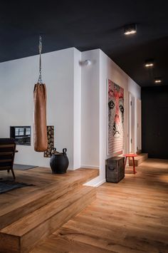 a living room with wooden floors and white walls, two boxing gloves hanging on the wall