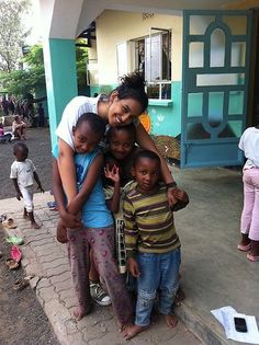 a group of children standing next to each other in front of a blue and yellow building