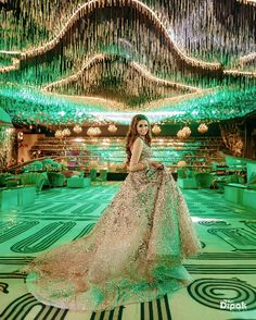 a woman in a long dress standing on a floor with chandeliers hanging from the ceiling