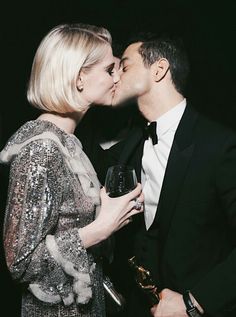 a man and woman kissing each other while holding wine glasses